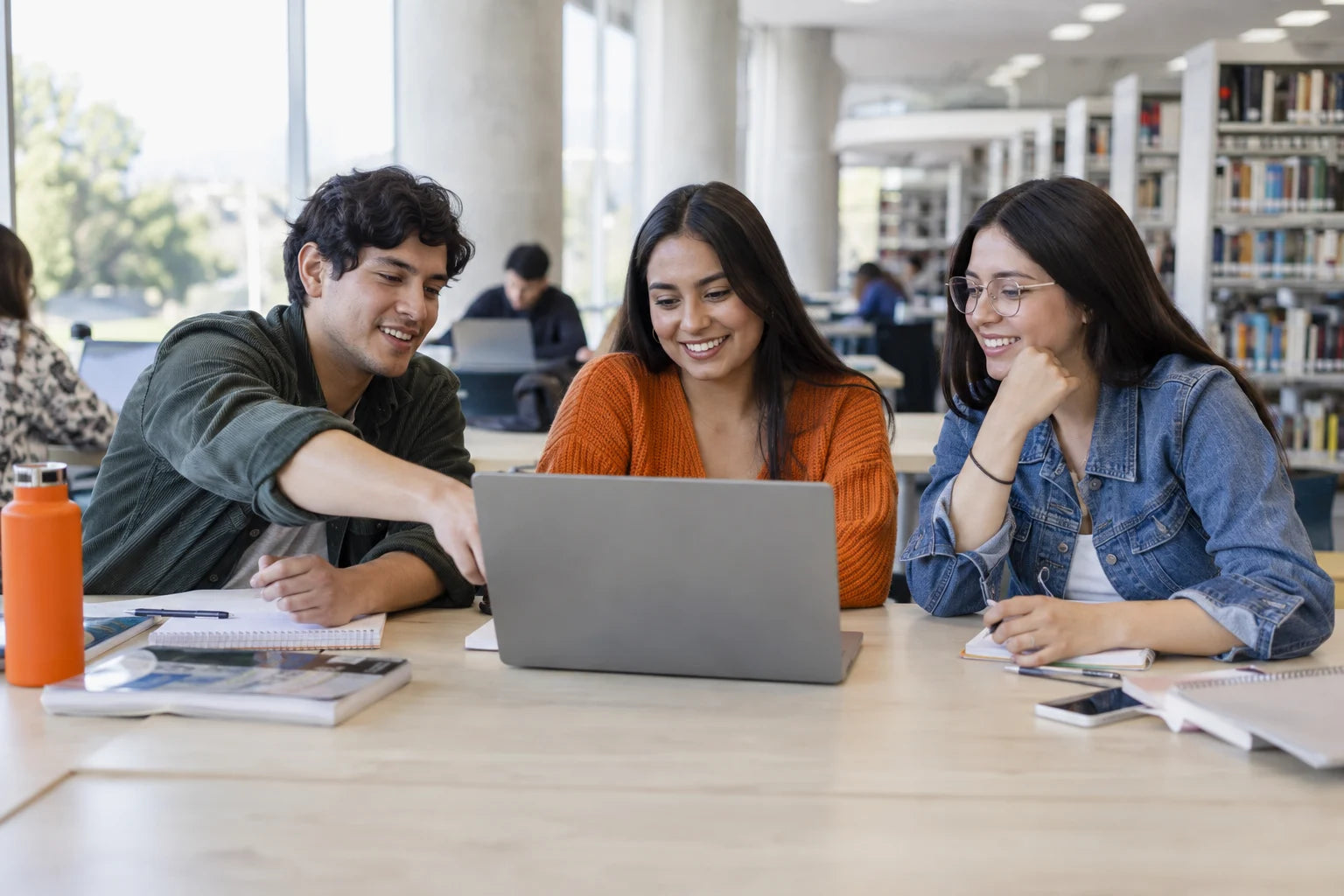 Estudiantes colaborando con un portátil en un espacio universitario